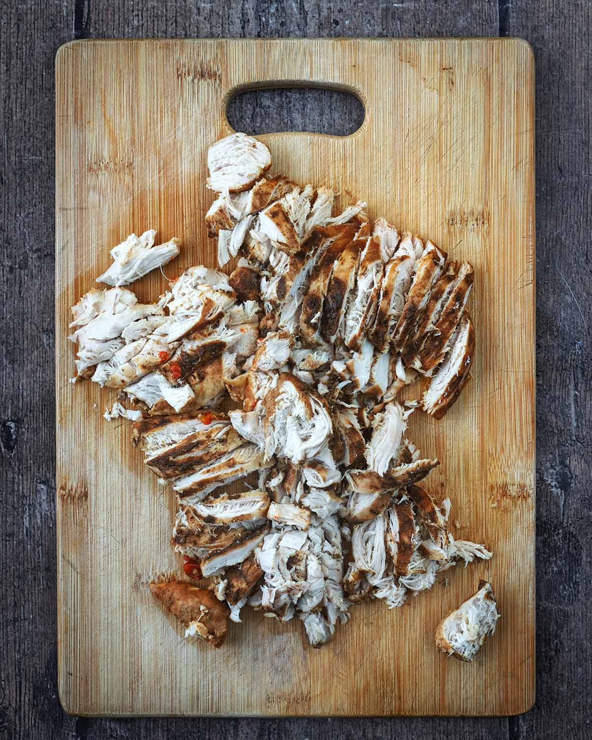 Chopped, seasoned chicken breast on a wooden chopping board.