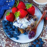 Easy Baked Oats on a white plate with fruit and a spoon
