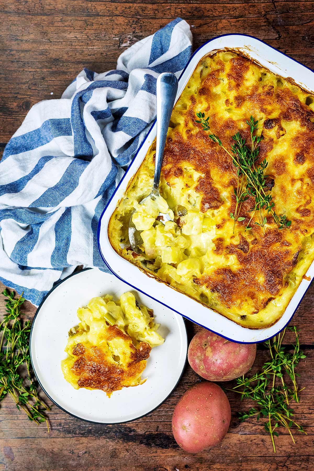 A baking dish full of potato bake next to a plate of more bake.