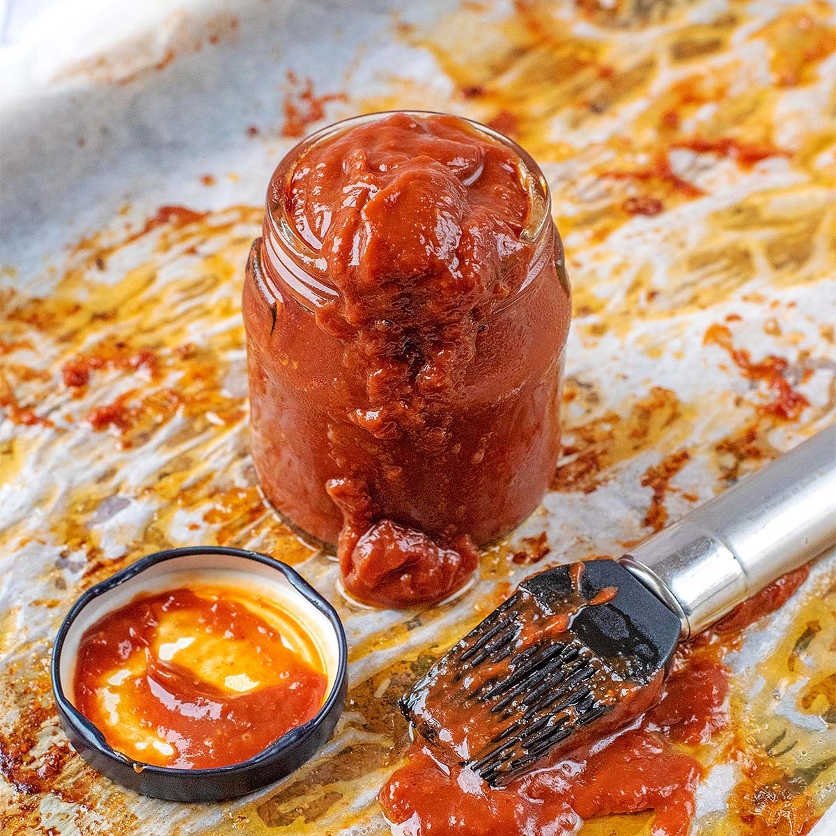 A small jar of healthy bbq sauce with a marinating brush in front of it.