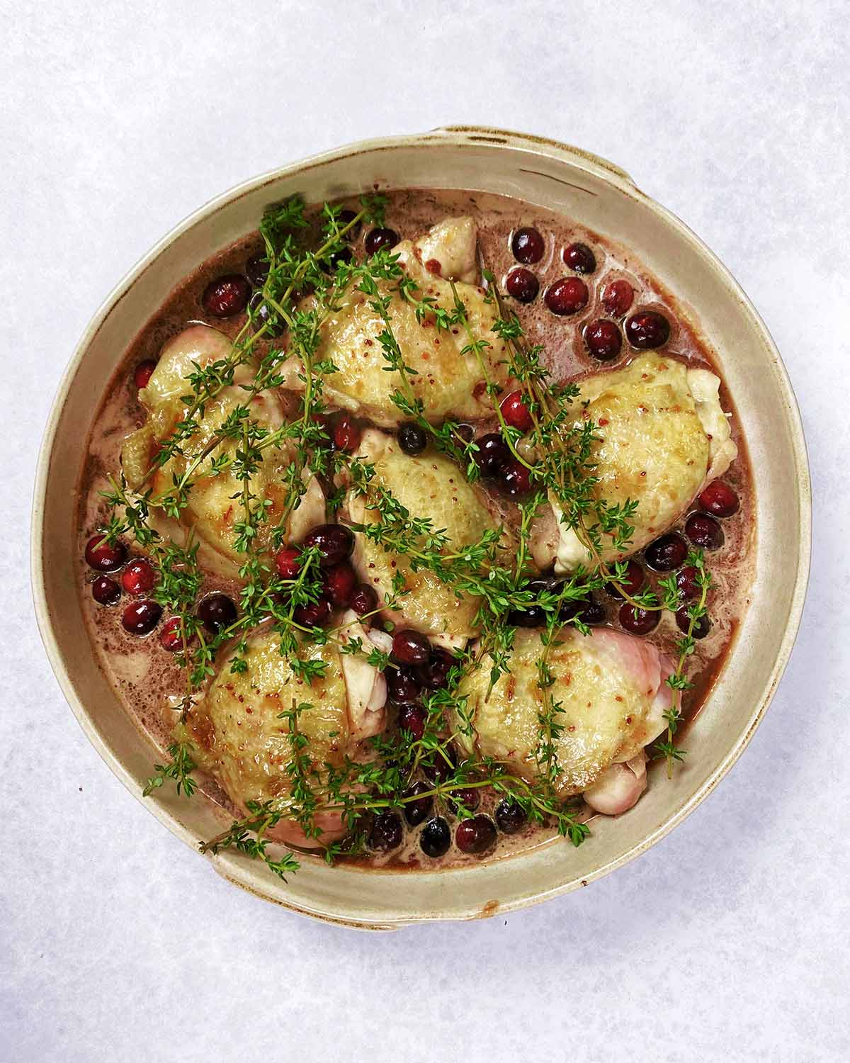 Whole cranberries and sprigs of thyme added to the chicken.