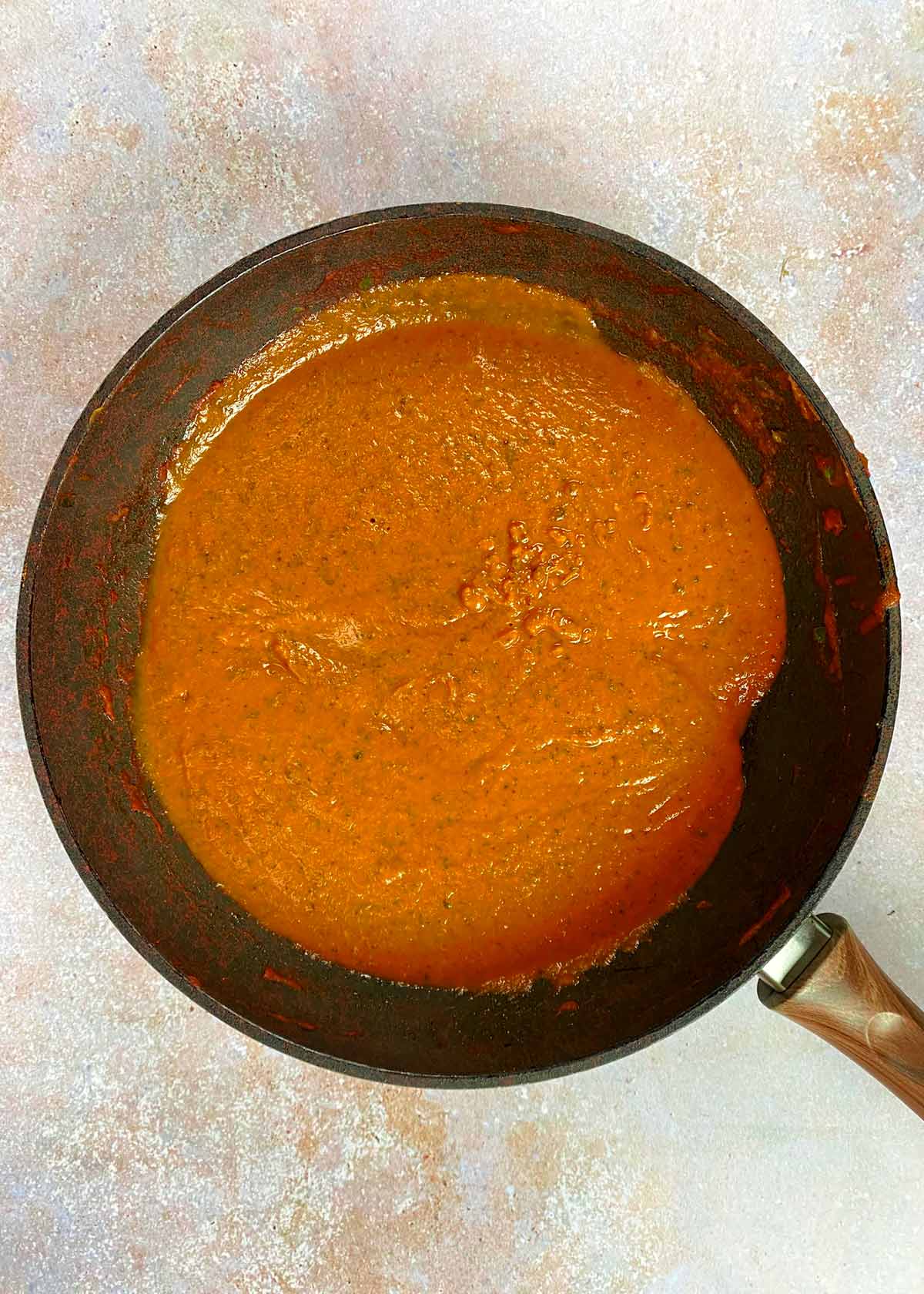A smooth, orange coloured curry sauce in a frying pan.