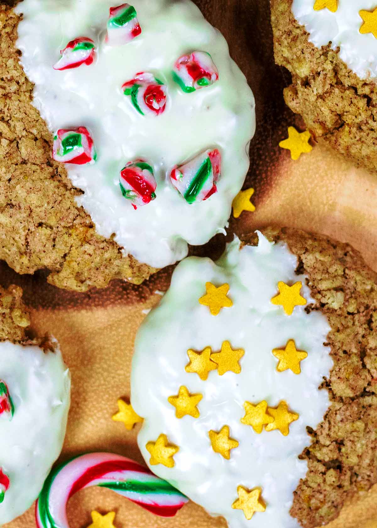 Two oat cookies, one decorated with crushed candy canes, one decorated with gold sugar stars.