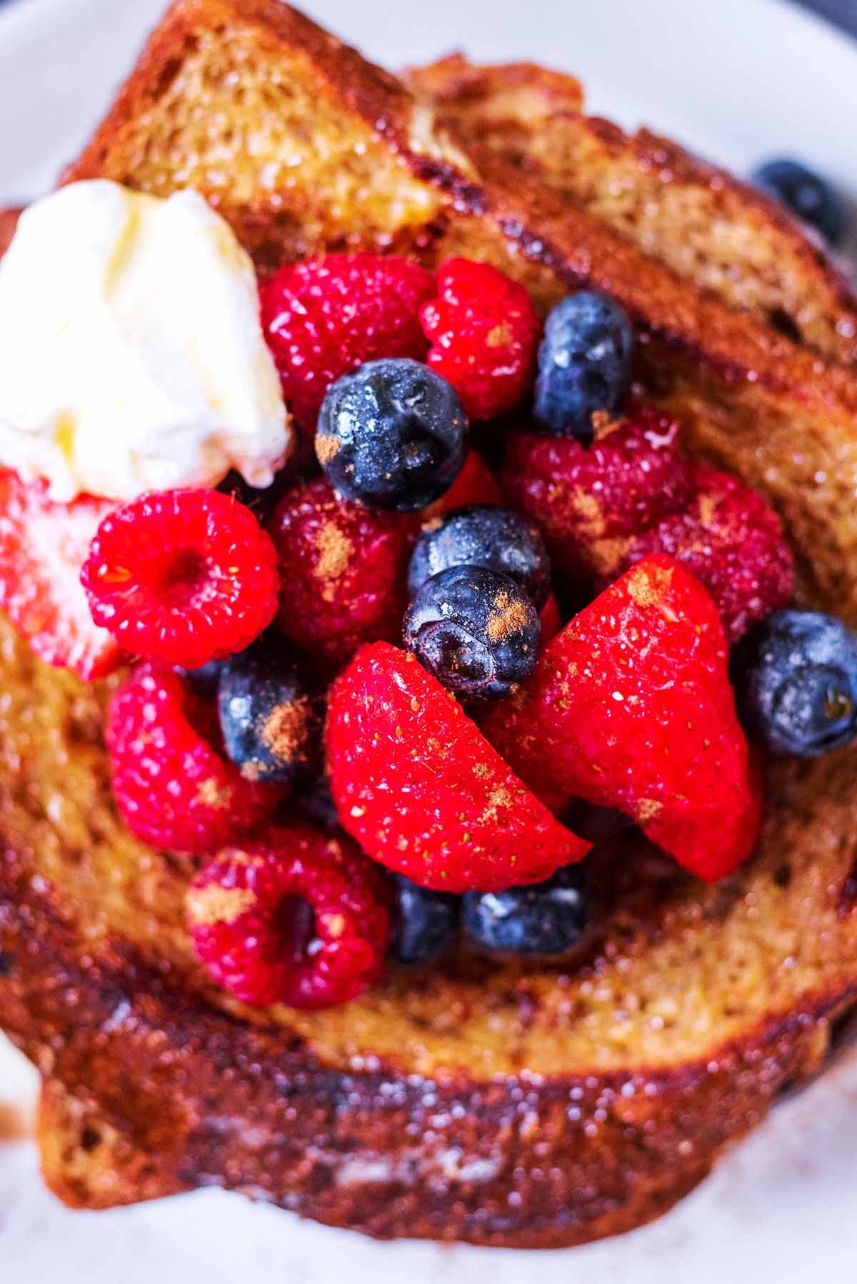 A mixture of berries on top of some French toast.