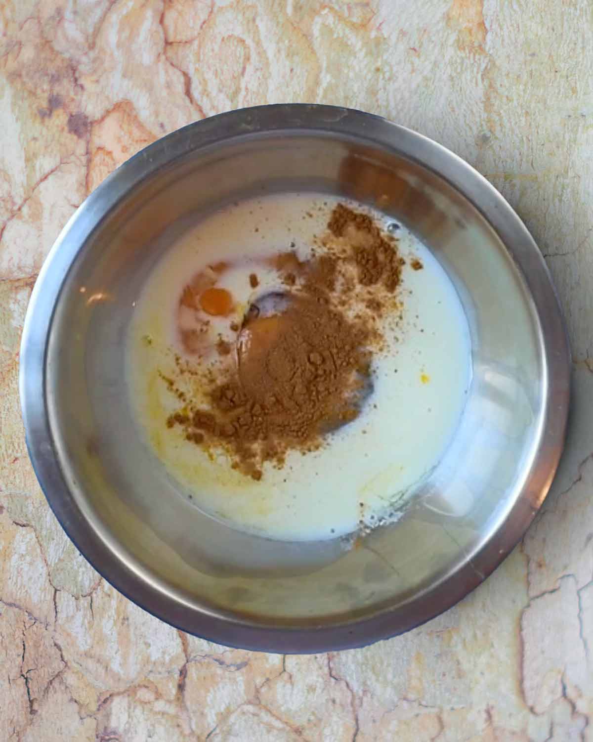 Eggs, milk and spices in a mixing bowl.