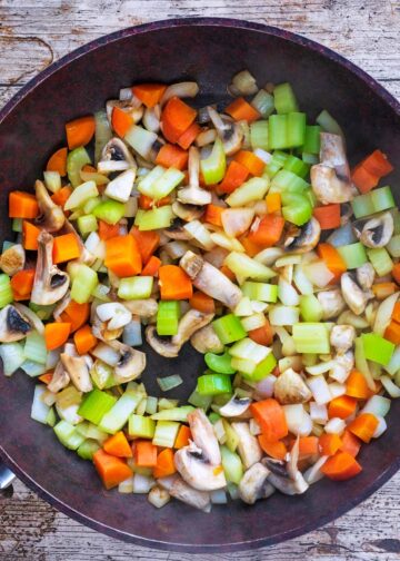 Chopped vegetables cooking in a frying pan.