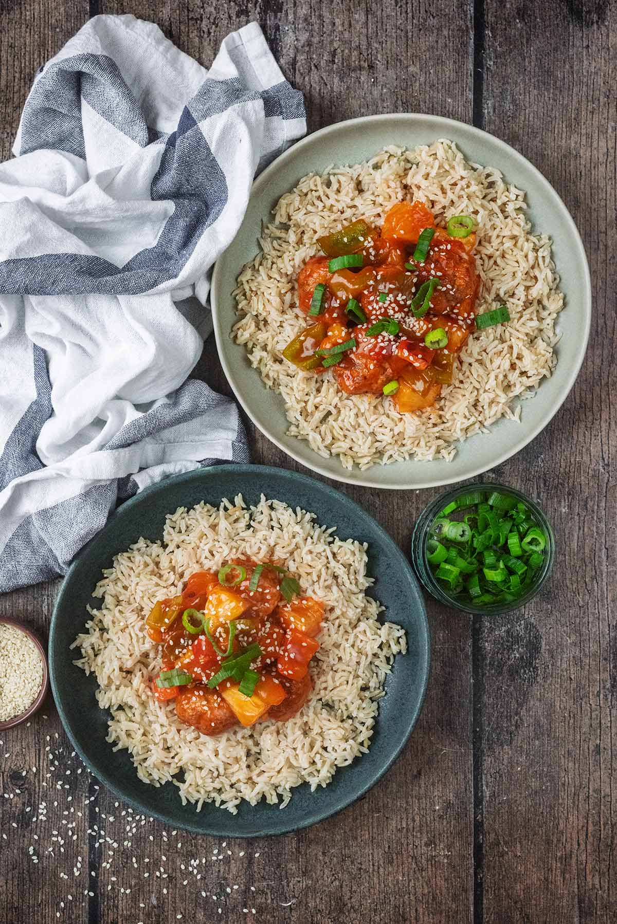 Two bowls of sweet and sour meatballs with rice.