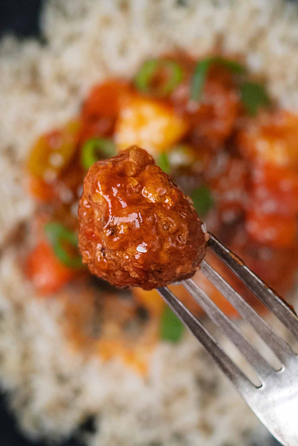 A fork holding a chicken meatballs.