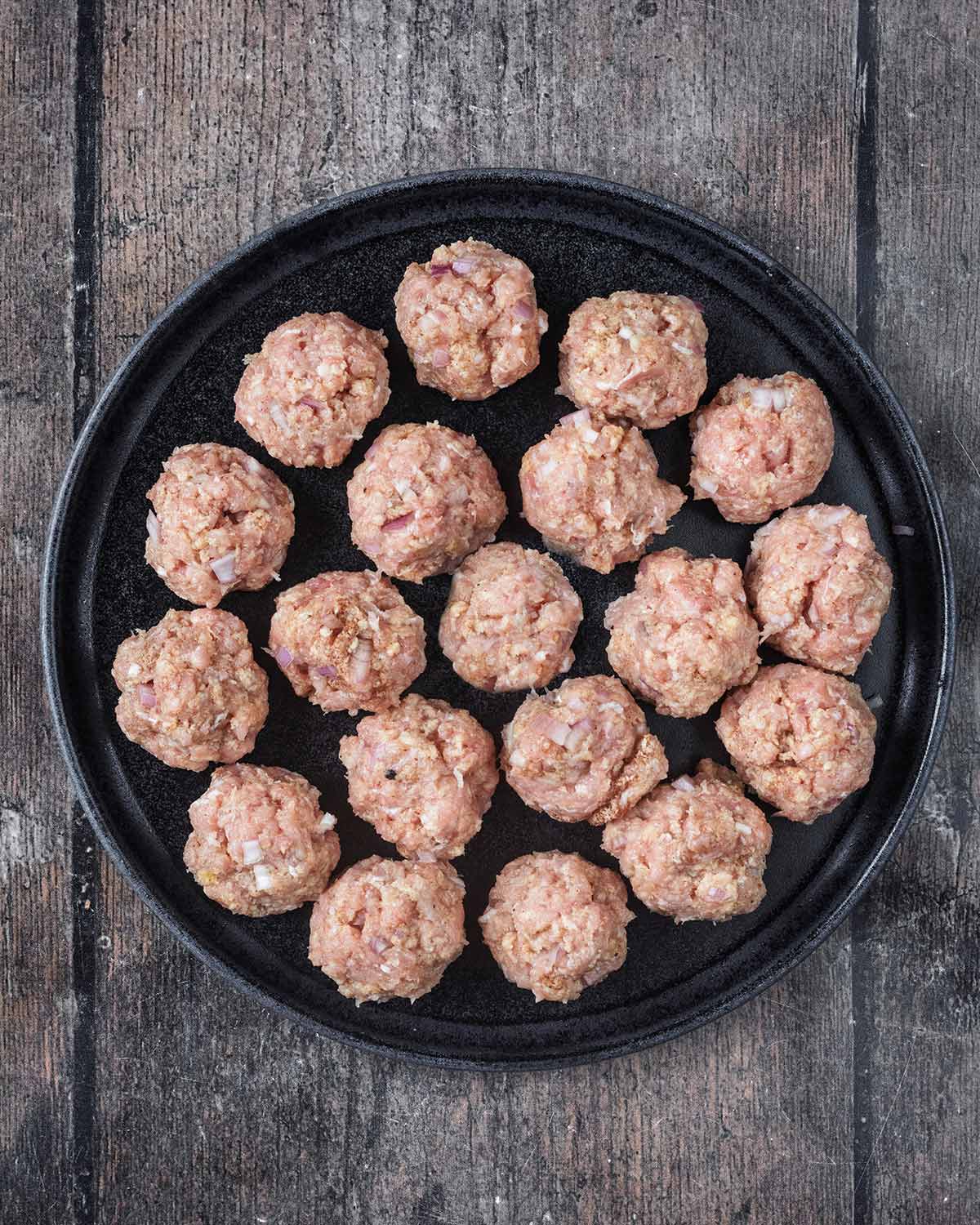 A plate of uncooked chicken meatballs.