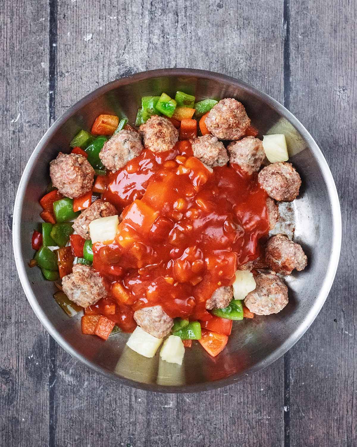 Pineapple chunks and sweet and sour sauce added to the pan.