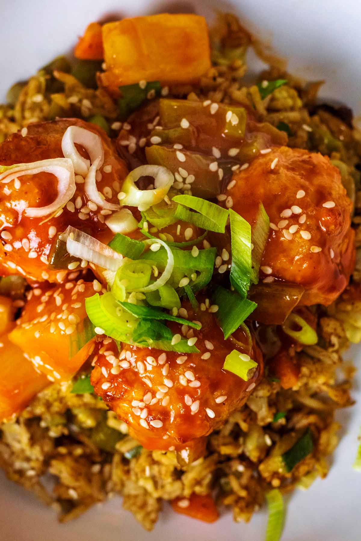 Meatballs on a bed of rice topped with sesame seeds and chopped spring onions.