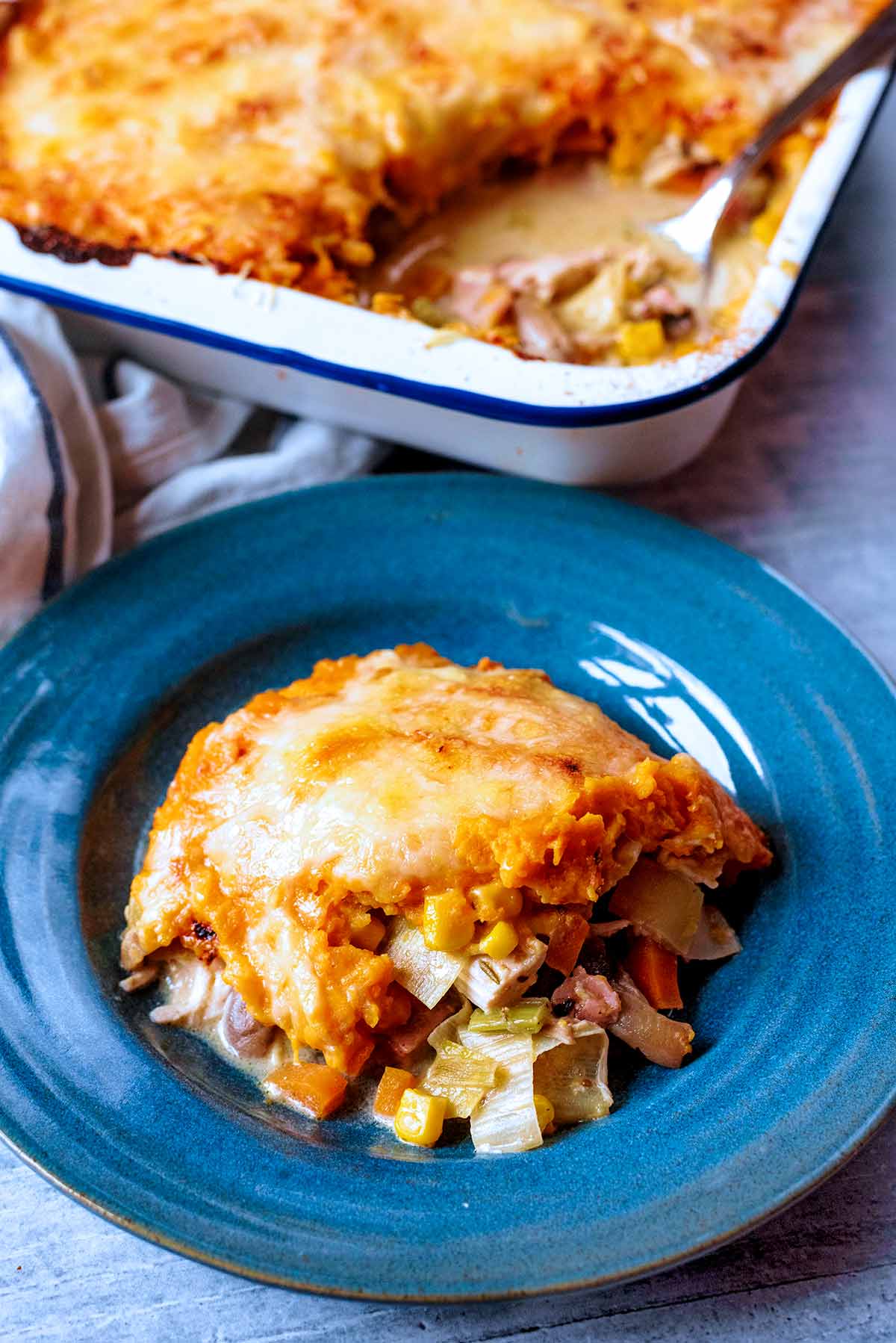 A plate of turkey pie in front of a baking tray of more pie.