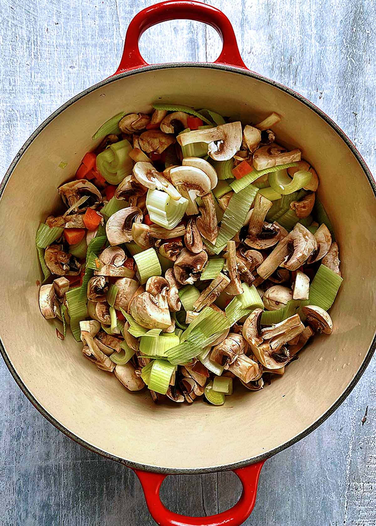 Mushrooms, leeks and carrots cooking in a large pot.