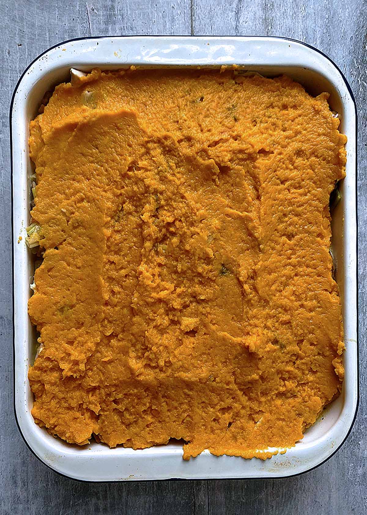 Mashed sweet potato topping on a pie in a baking dish.