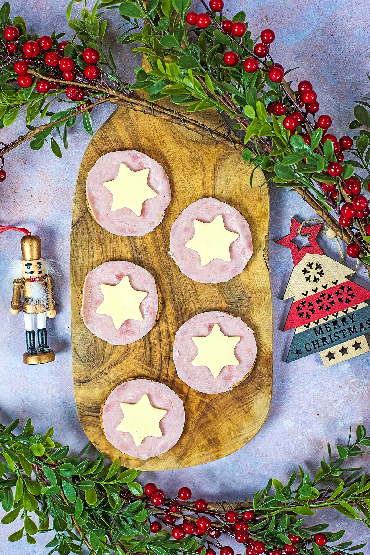 A serving board with crackers, ham and star shaped cheese.