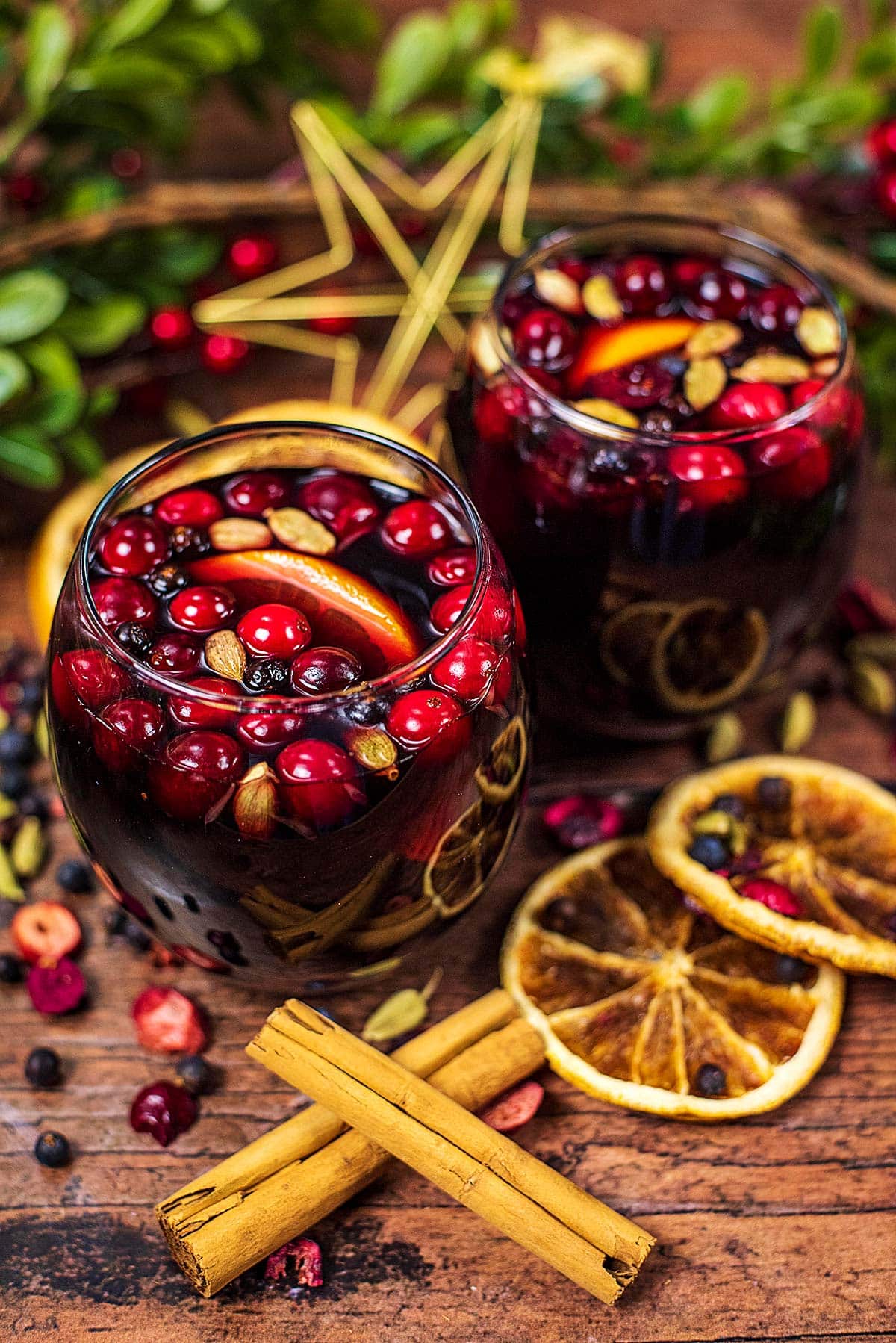 Two glasses of mulled wine surrounded by fruit and Christmas decorations.