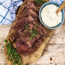 Slow Cooker Roast Beef on a board with some horseradish sauce.