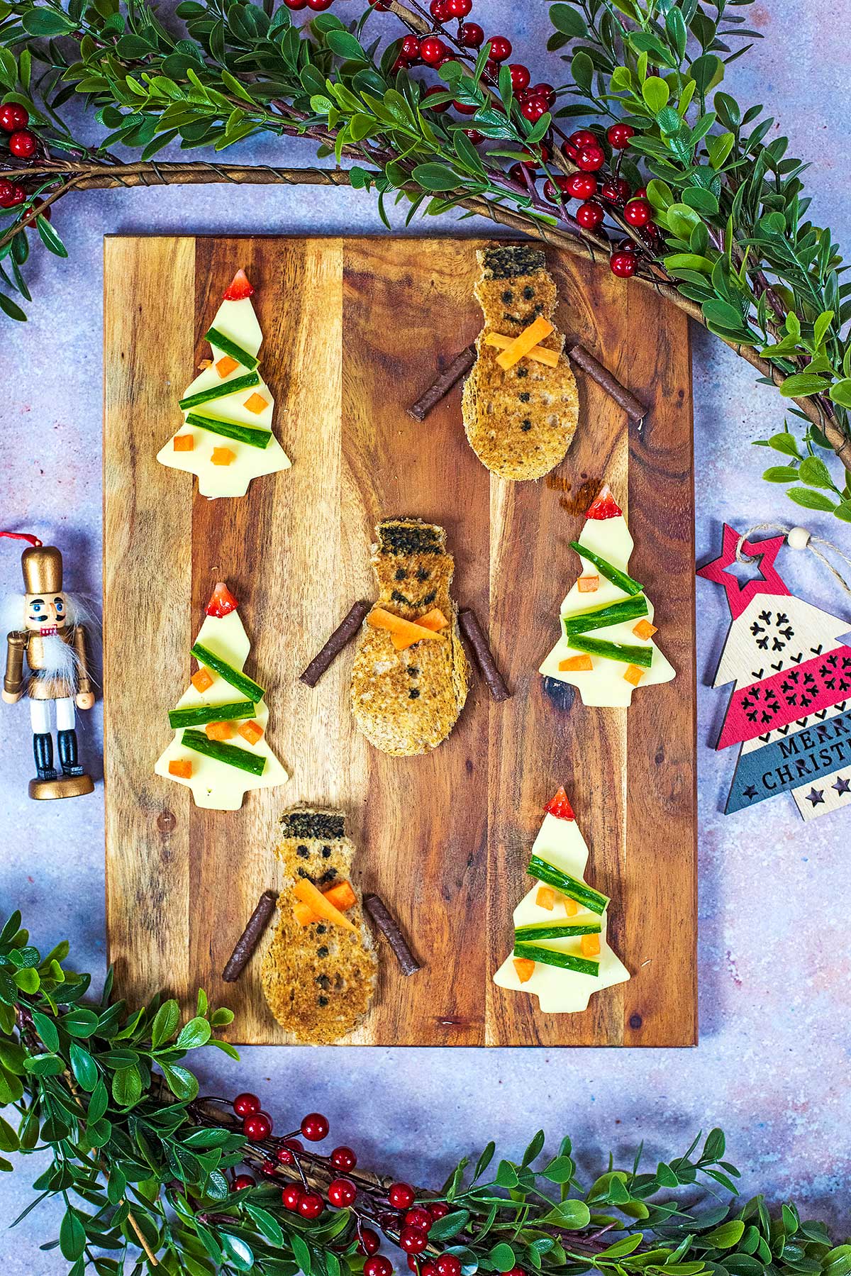 Slices of toast cut into a snowman shape with slices of cheese in tree shaped.
