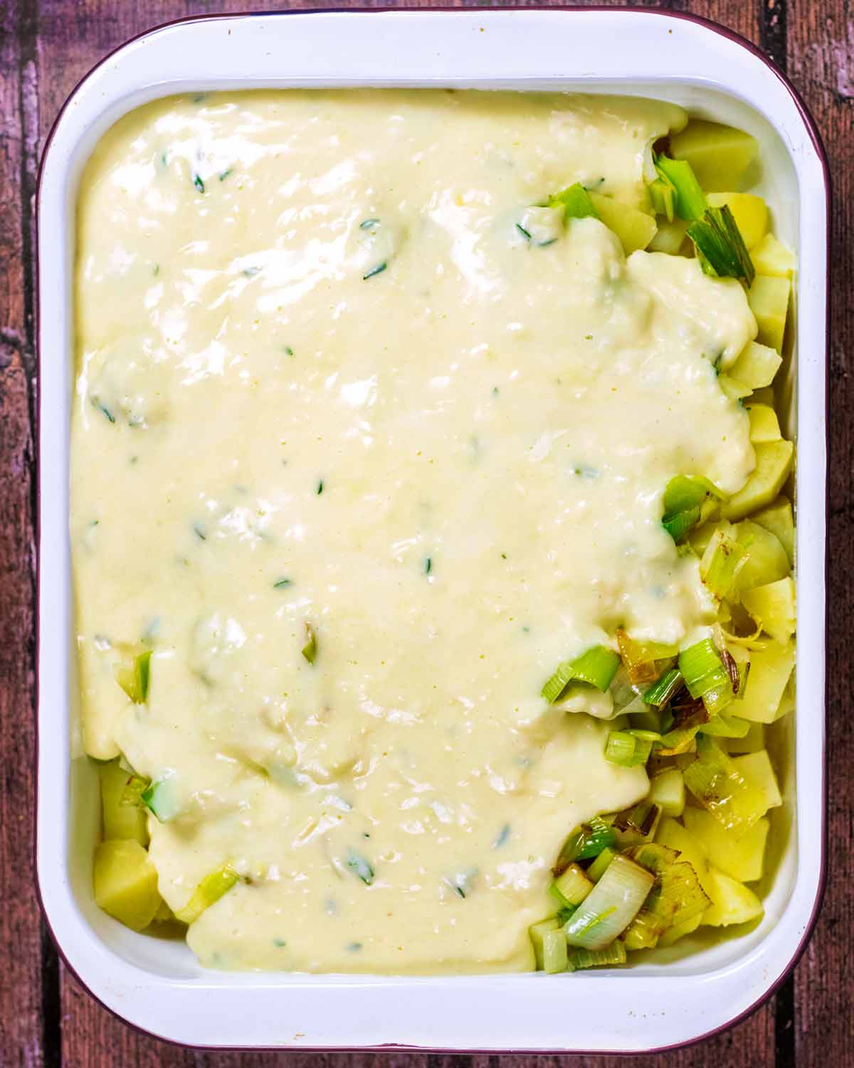 Cheese sauce poured over the potatoes, leeks and onions.