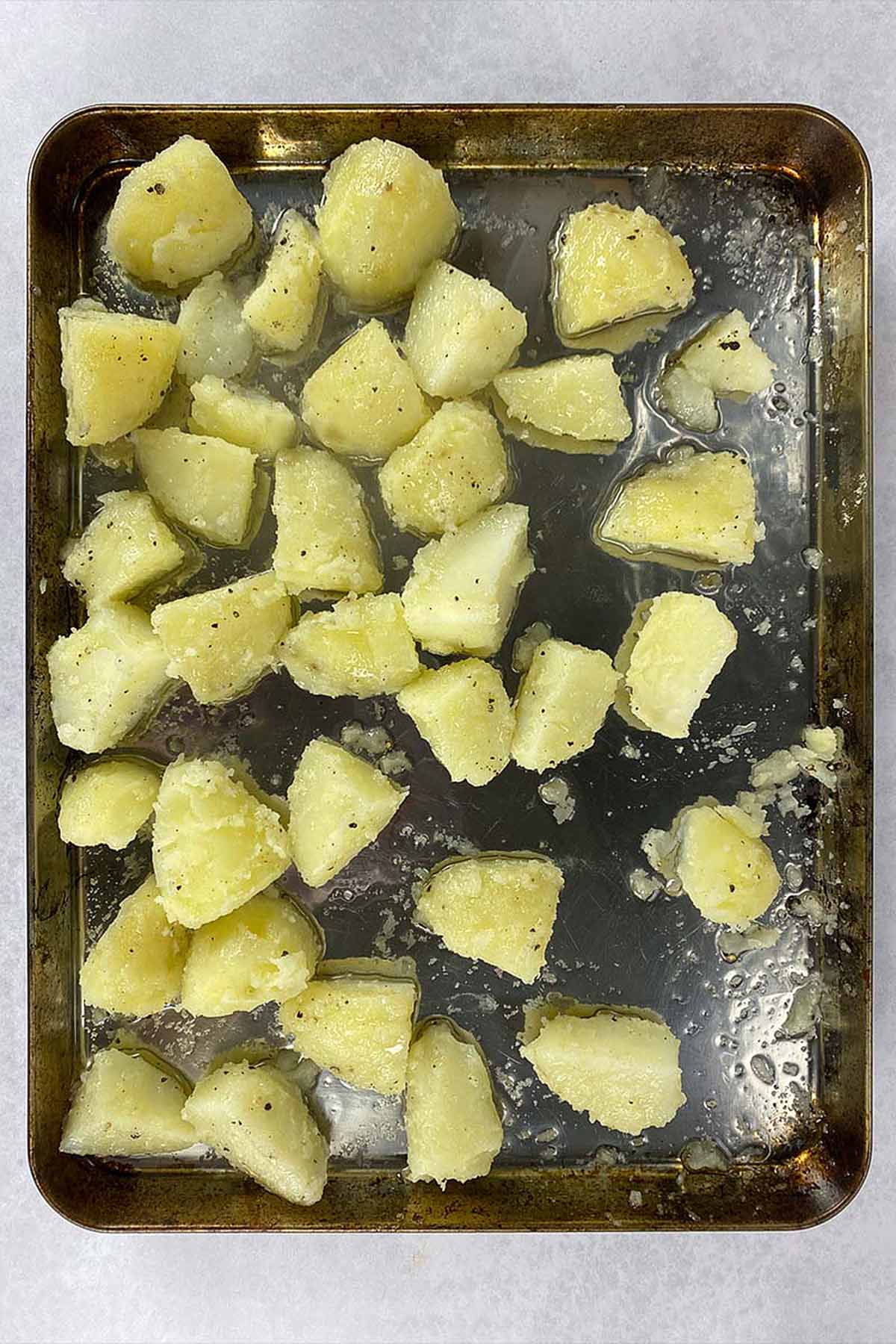 Boiled potatoes spread over a large baking sheet.