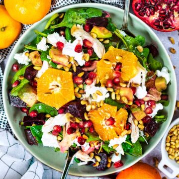 Clementine and leftover turkey salad in a bowl topped with pine nuts and pomegranate seeds.