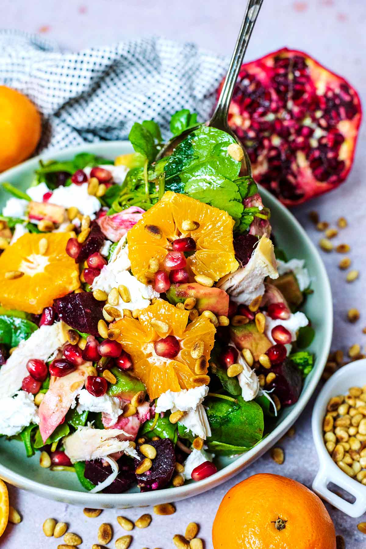 A bowl of clementine salad in front of half a pomegranate.