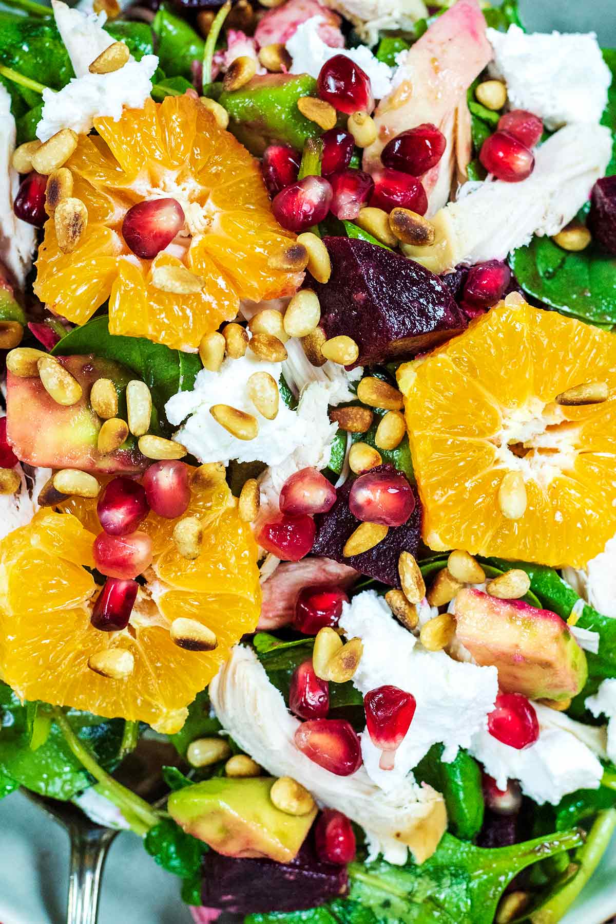 Sliced clementines and pomegranate seeds with goat's cheese and salad leaves.