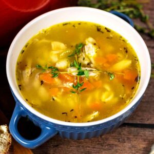 A bowl of leftover turkey soup with two sprigs of thyme on top.