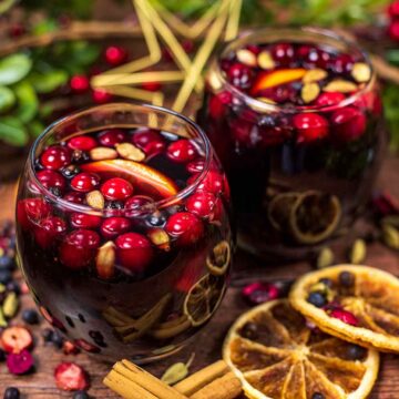 Slow Cooker Mulled Wine in tumblers with cranberries and orange slices.