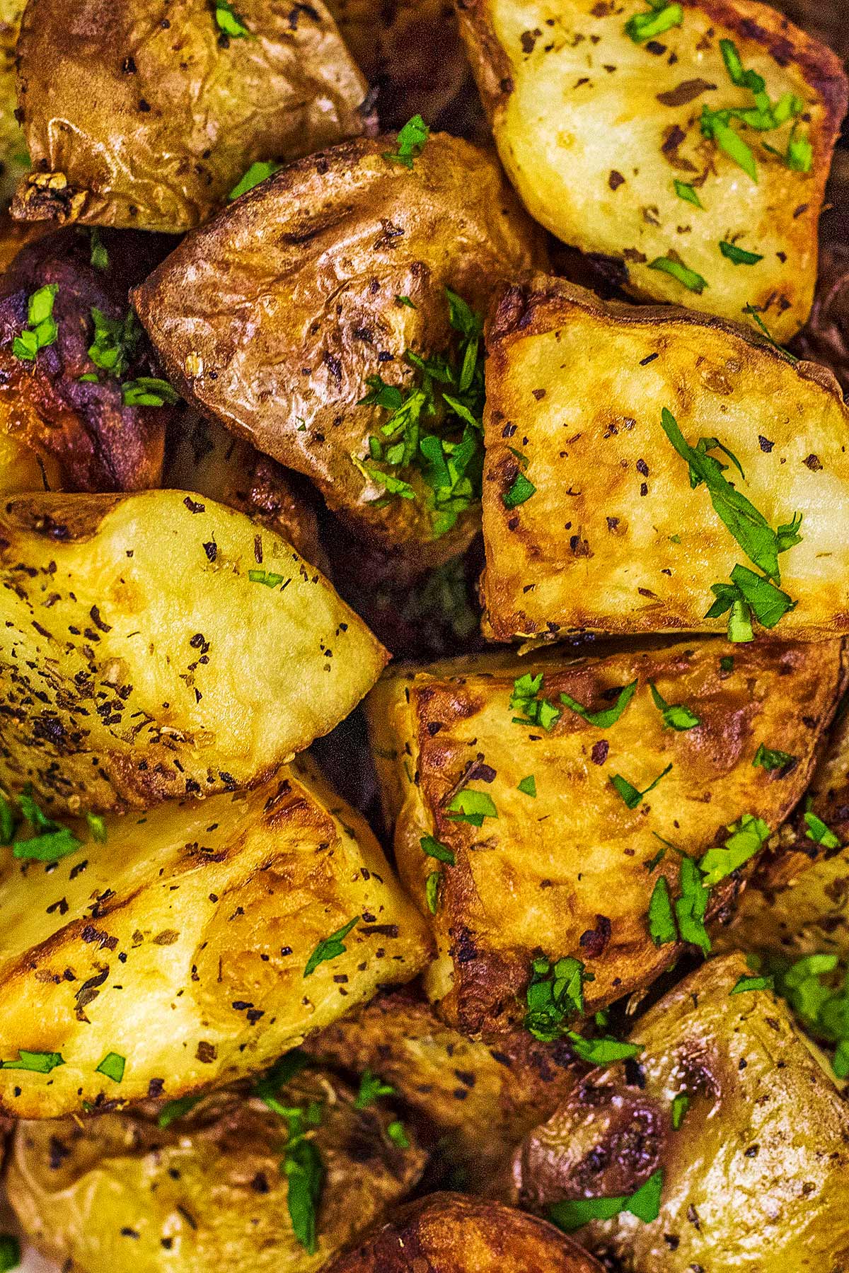 Roasted potatoes with chopped herbs sprinkled over them.