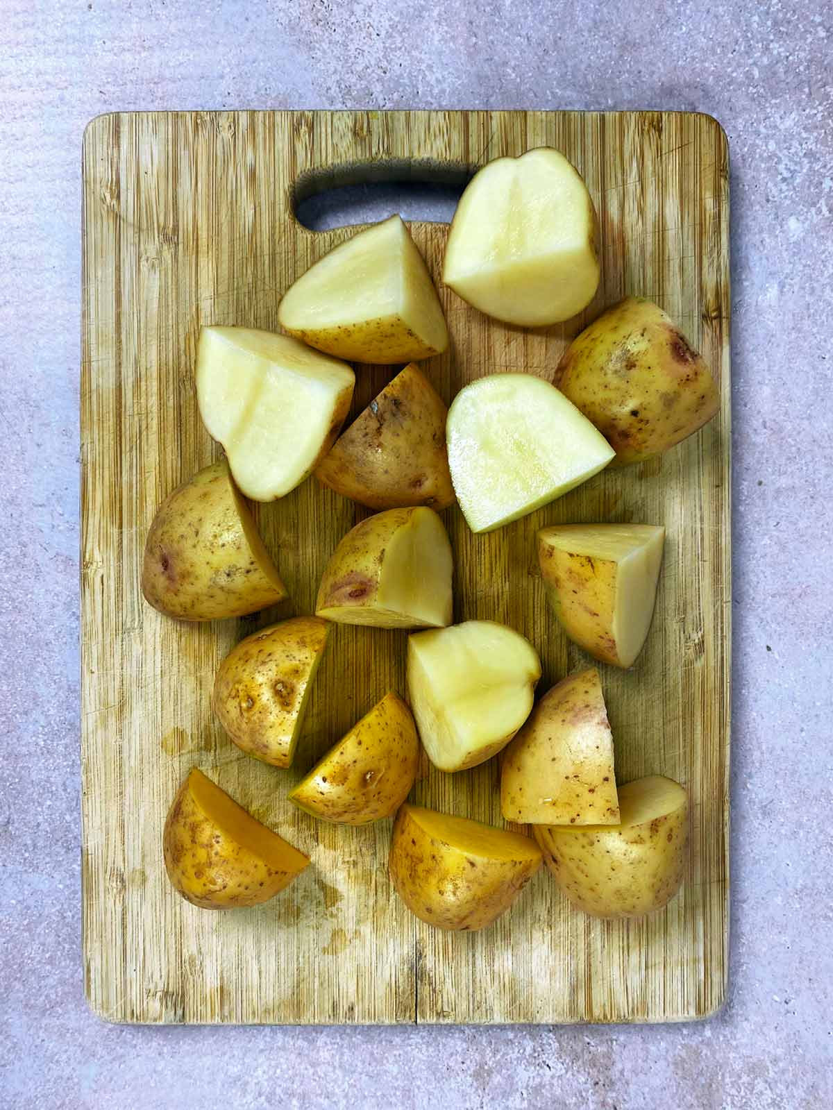 A chopping board with chopped potatoes on it.