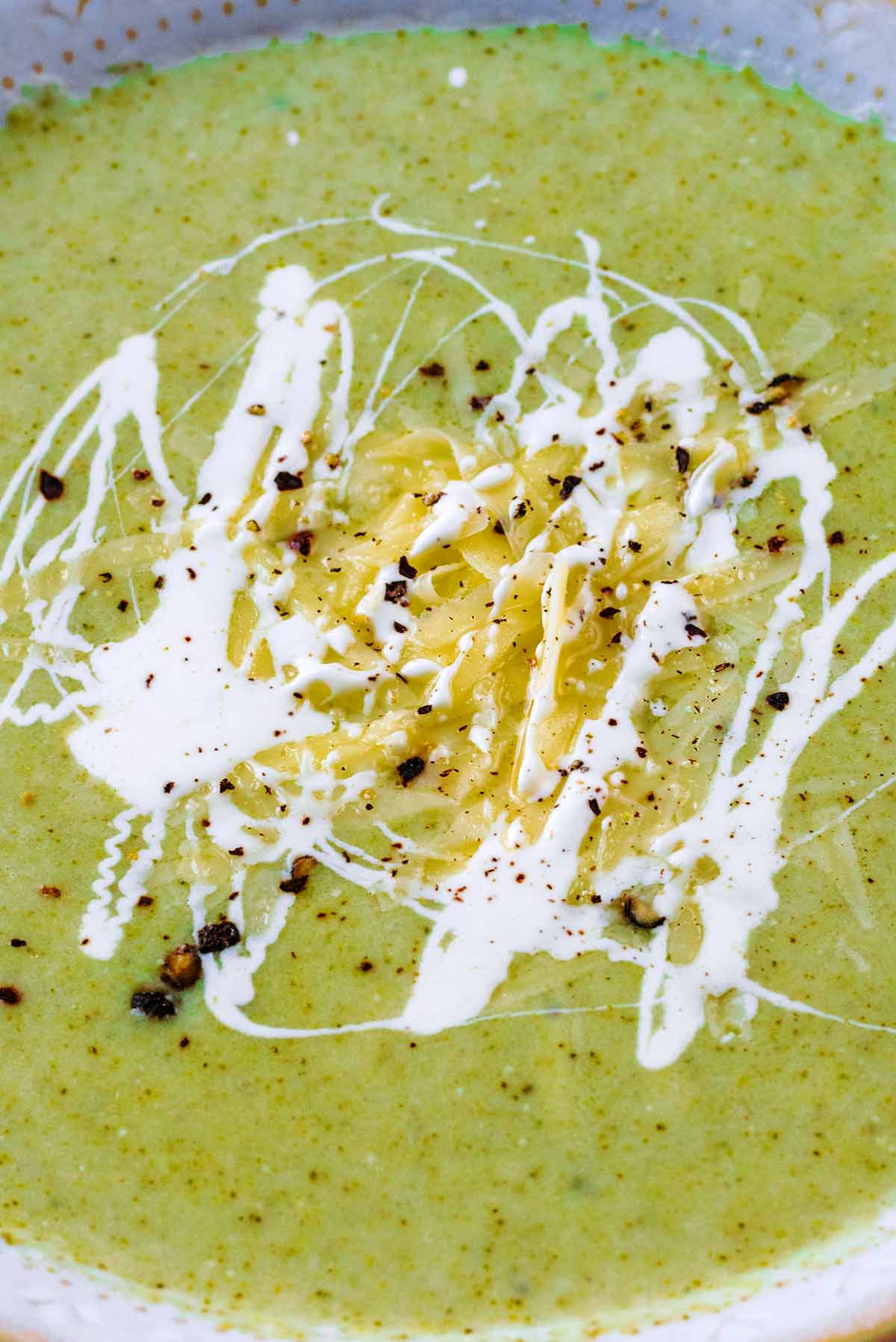 Grated cheese and cream on the surface of some soup.