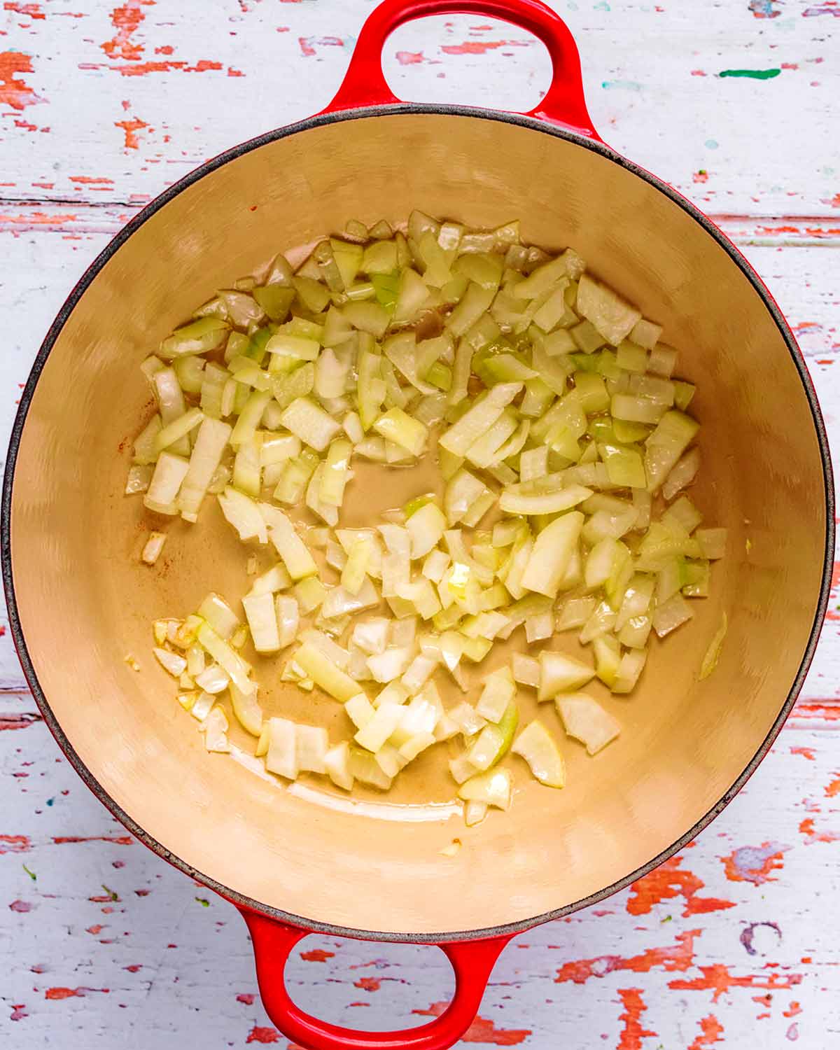Chopped onions sautéing in a large pan.
