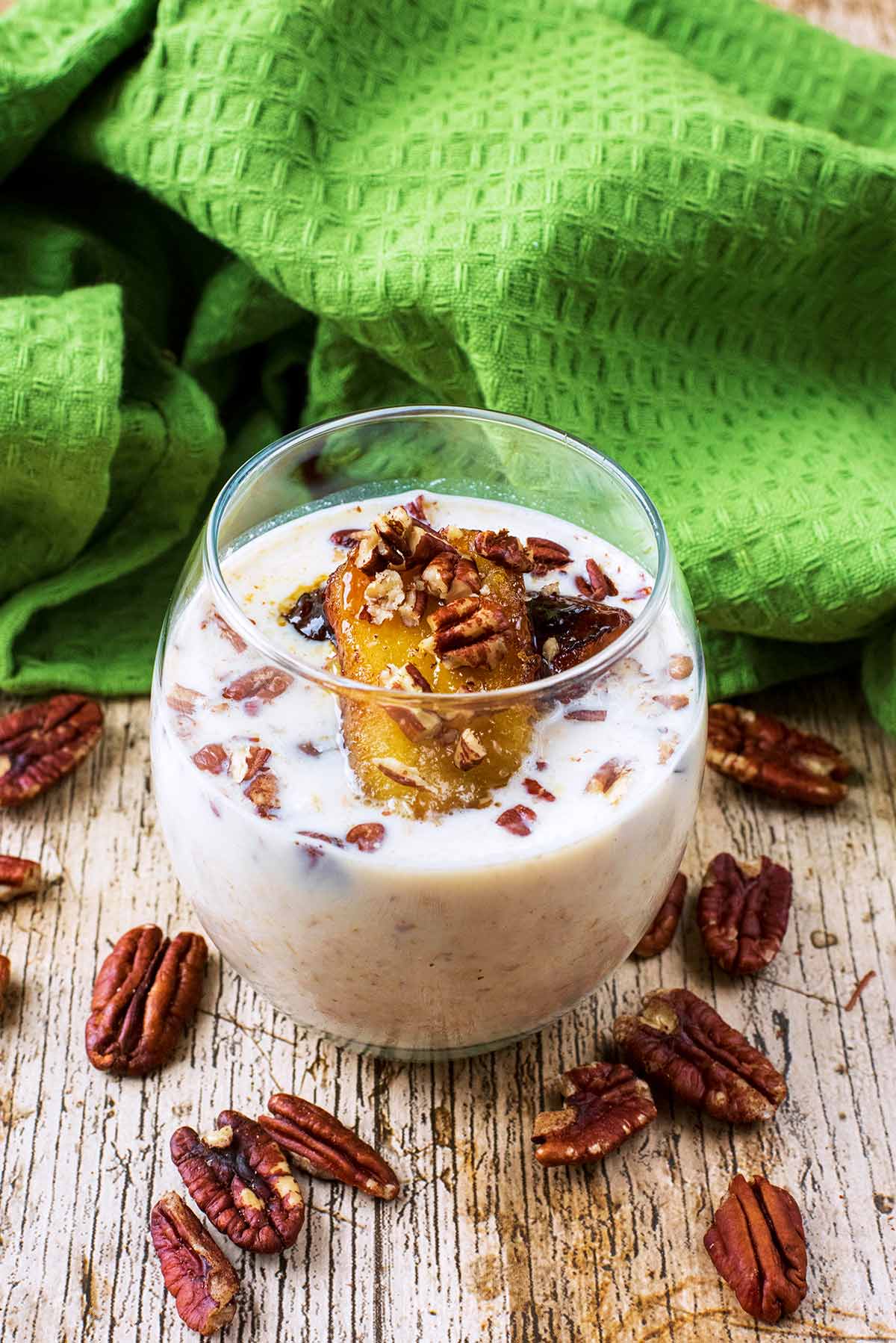 A glass of overnight oats topped with a caramelised banana slice and pecans.