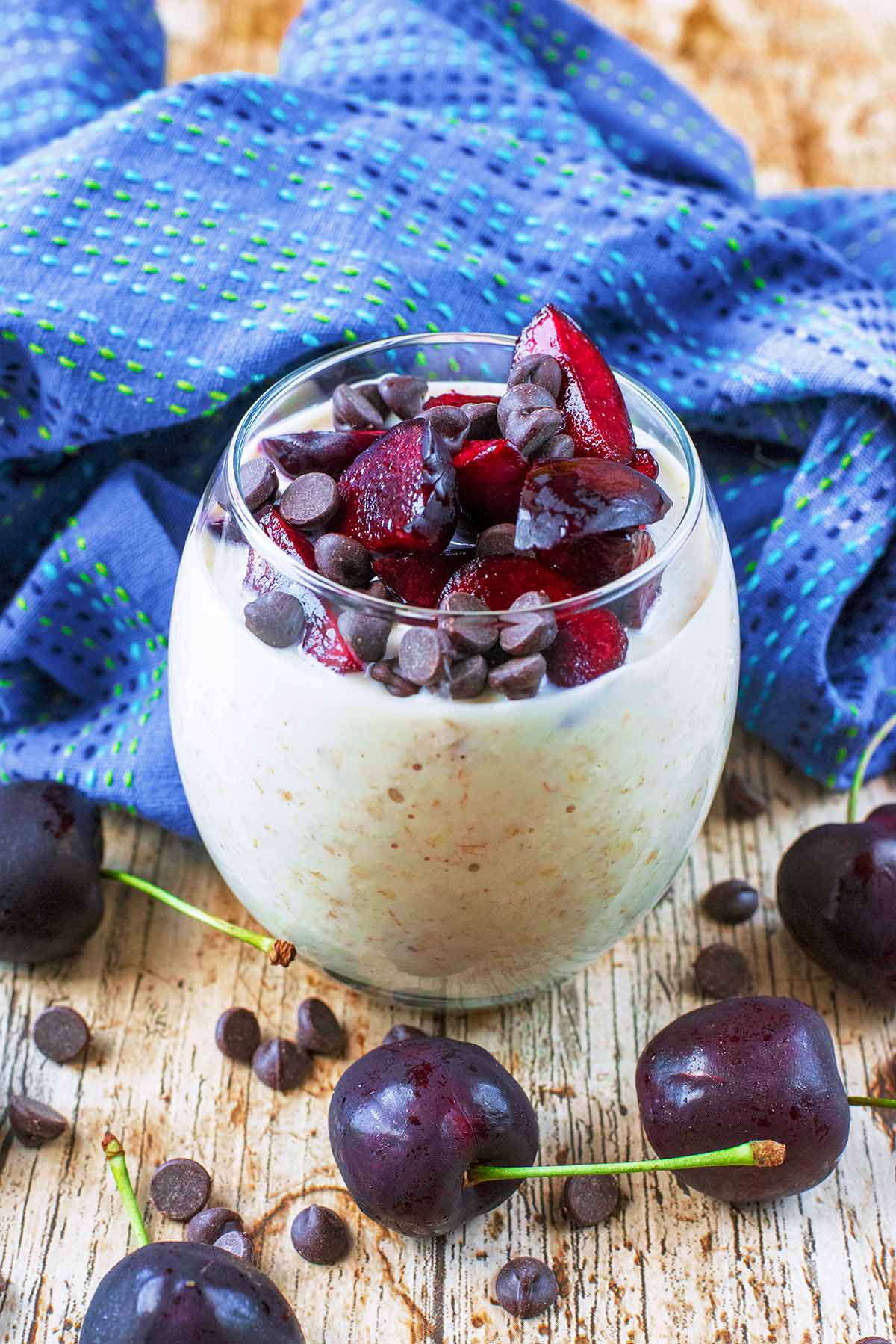 A glass of overnight oats topped with cherries and chocolate chips.