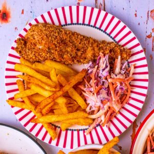 A piece of Healthy KFC on a plate with fries and slaw.