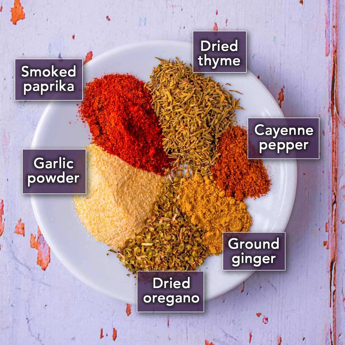 Six different herbs and spices on a white plate.