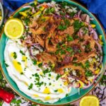 Slow cooked lamb on a plate with rice salad and yogurt.