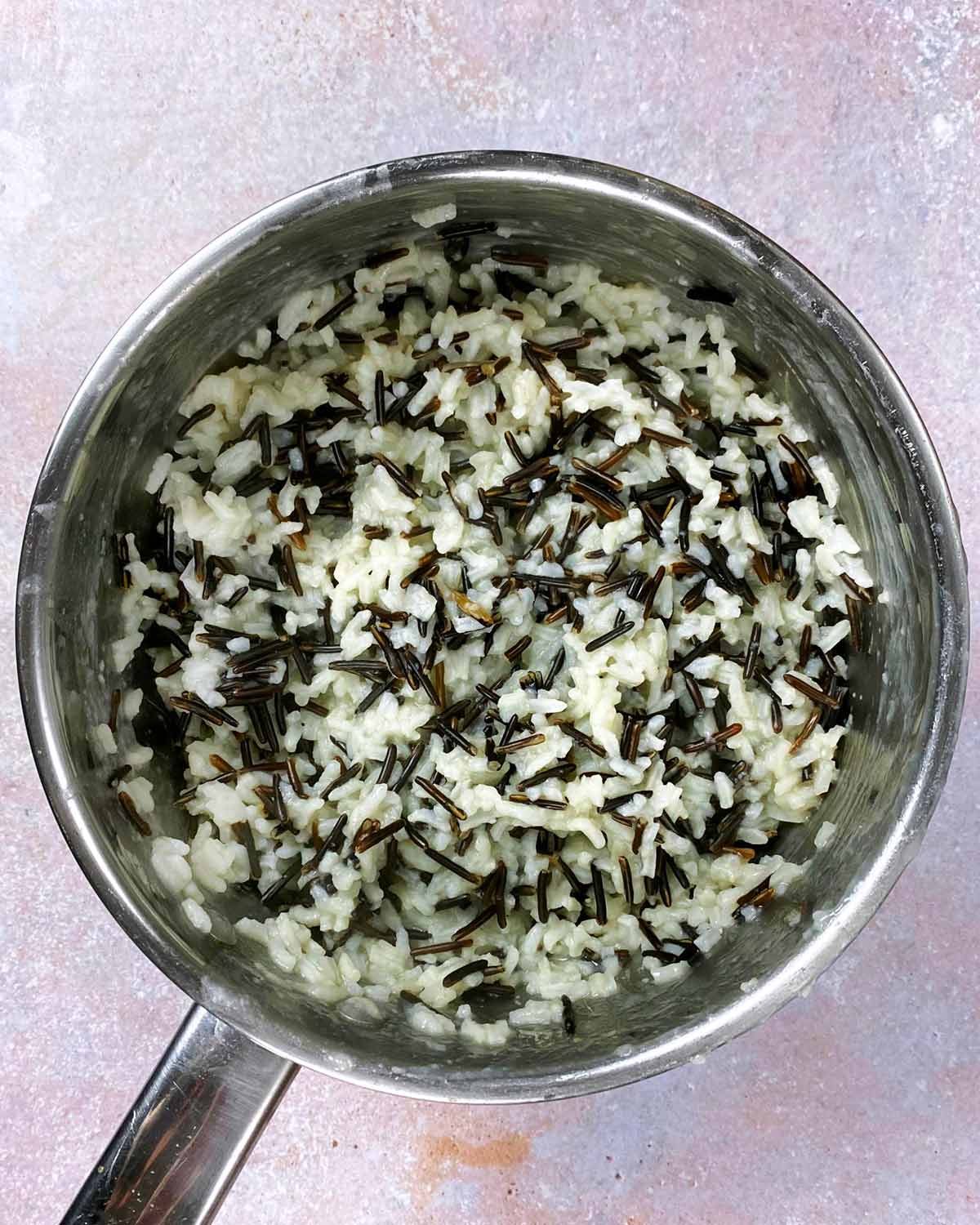 A saucepan containing cooked black and white rice.