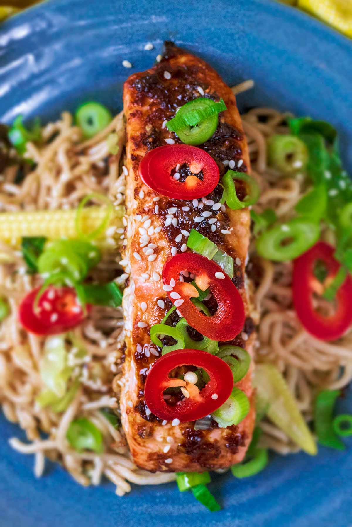 Cooked salmon fillet topped with sliced red chilli and sesame seeds.