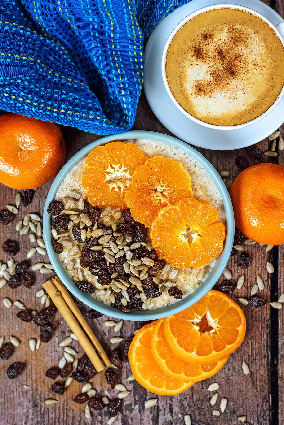 A bowl of porridge topped with sliced oranges next to a cup of coffee.