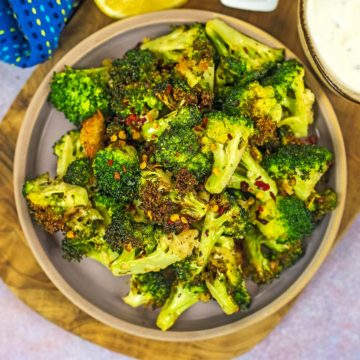 A plate of crispy air fryer broccoli florets with chilli flakes on top.