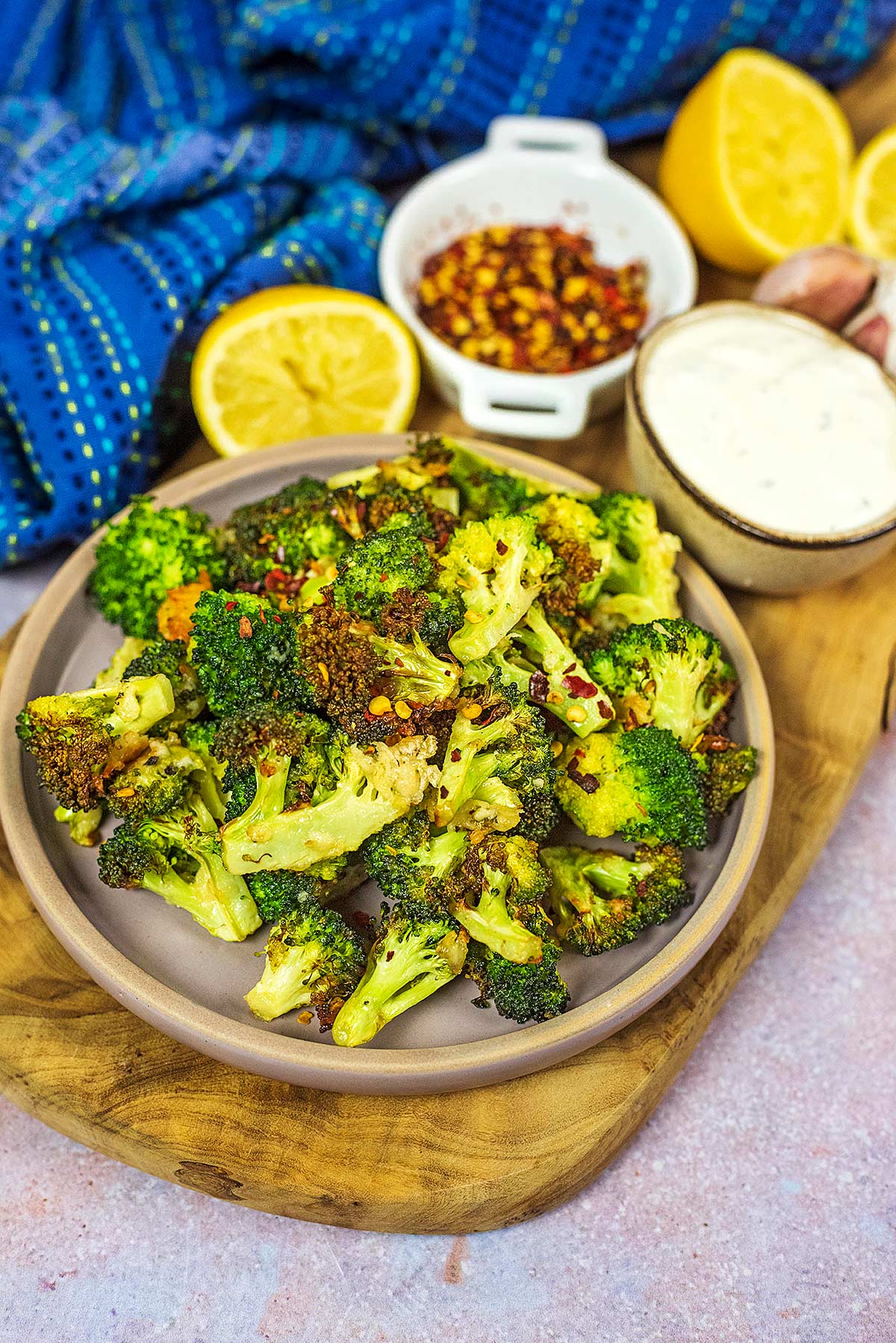 A wooden serving board with a plate of cooked broccoli on it.