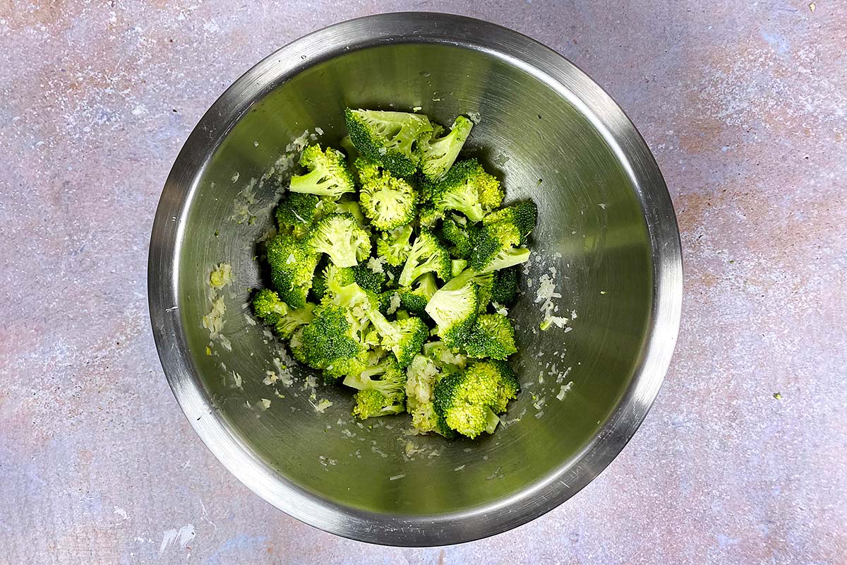 A bowl of broccoli florets coated in garlic and herb oil.