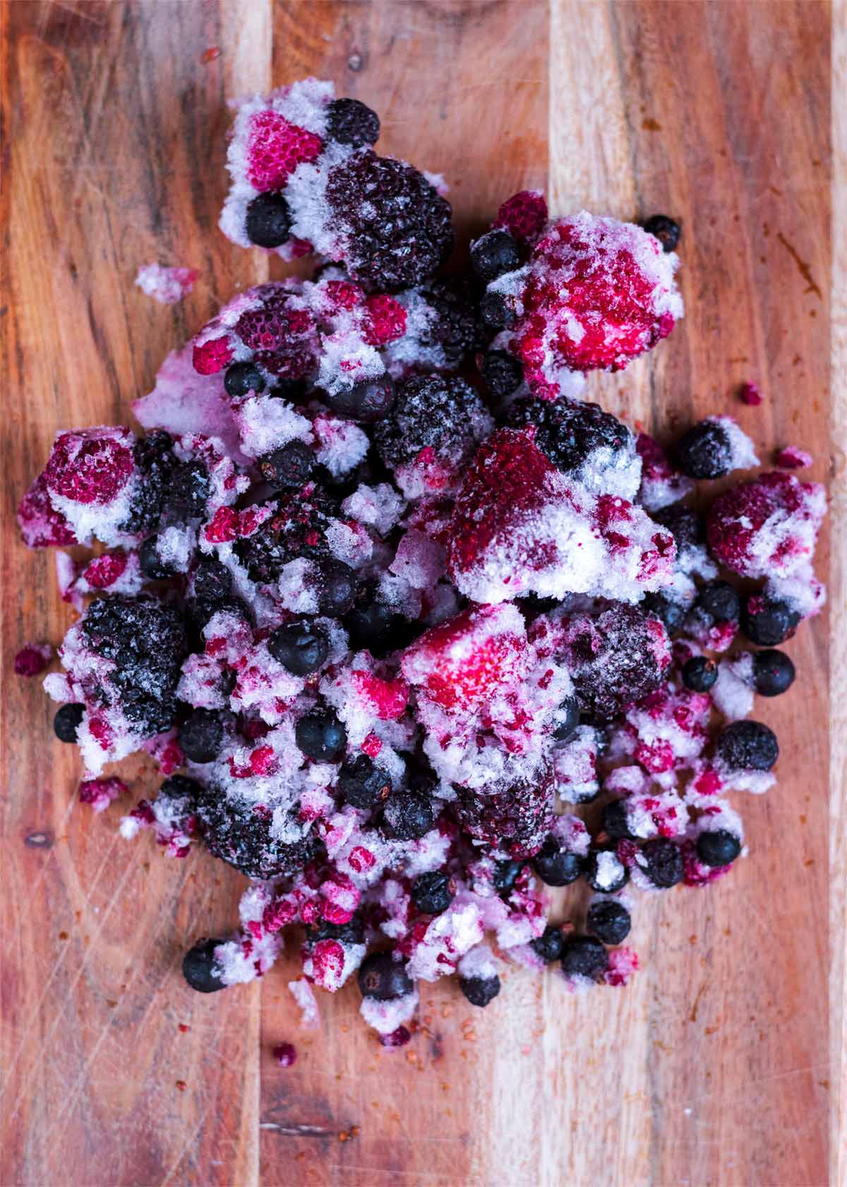 A pile of frozen berries on a wooden board.