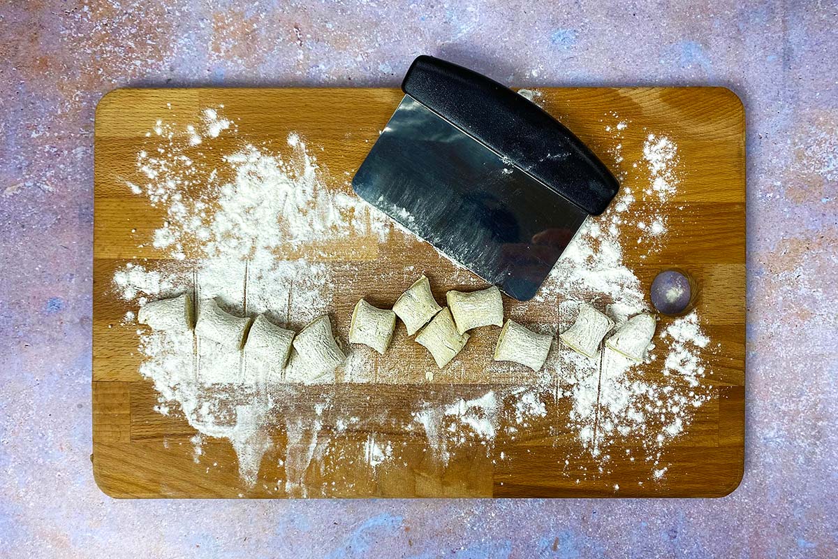 A chopping board with cut gnocchi on it.