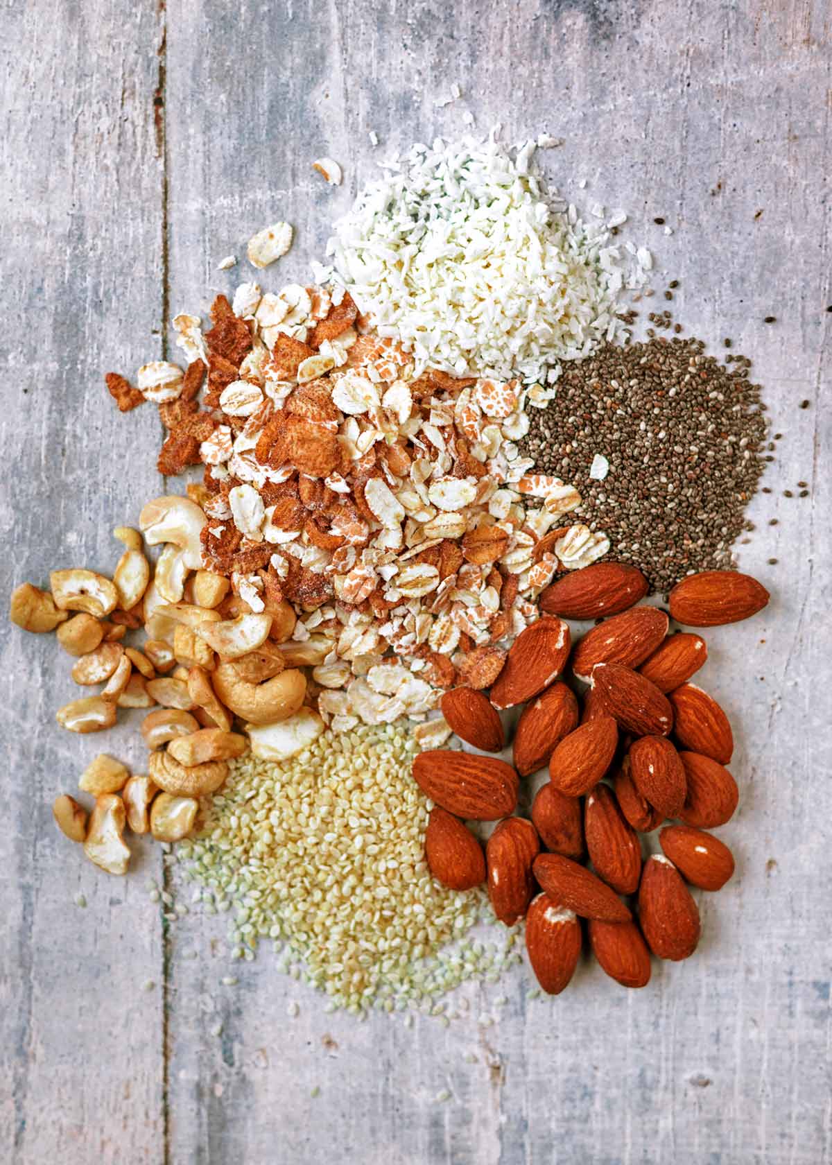 A selection of oats, nuts and seeds on a wooden surface.