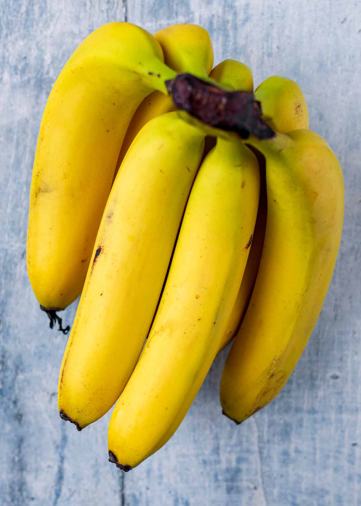 A bunch of bananas on a wooden surface.