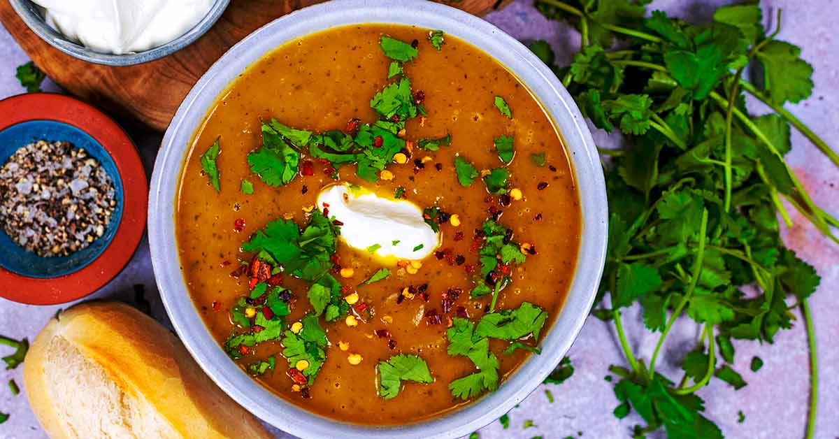 Carrot and coriander soup in a round blue bowl.