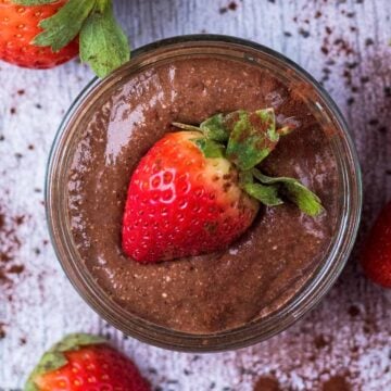 A pot of Chocolate Chia Pudding topped with half a strawberry.